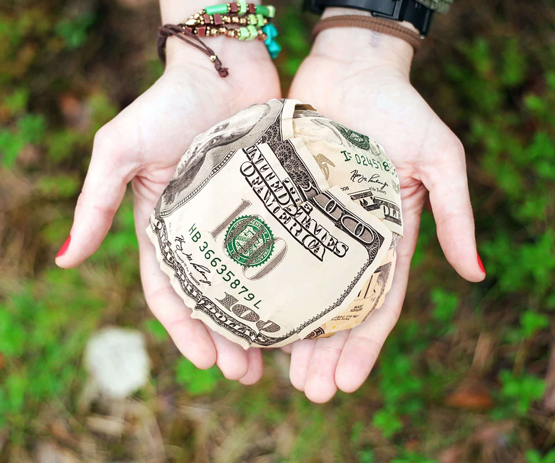 Hands holding a ball made from banknotes